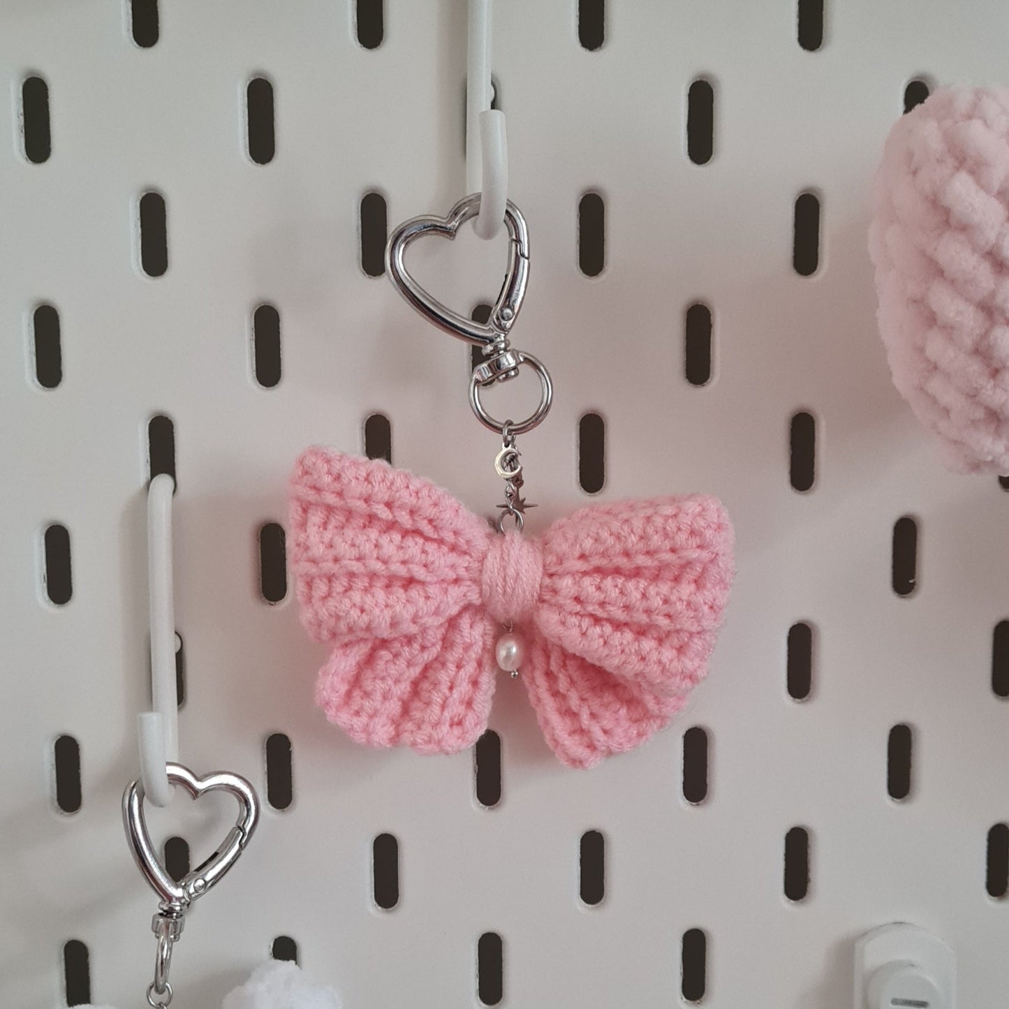 Porte-clés Magical Bow en crochet. Ce porte-clés Nœud est aussi mignon et délicat que celui d'une Magical Girl ! Il est agrémenté d'une perle et de pendentifs lune et étoile, ce qui en fait le parfait accessoire coquette à accrocher à votre sac ou à suspendre chez vous pour une déco mignonne. Chaque objet est crocheté et assemblé à la main, pour un rendu de haute qualité.