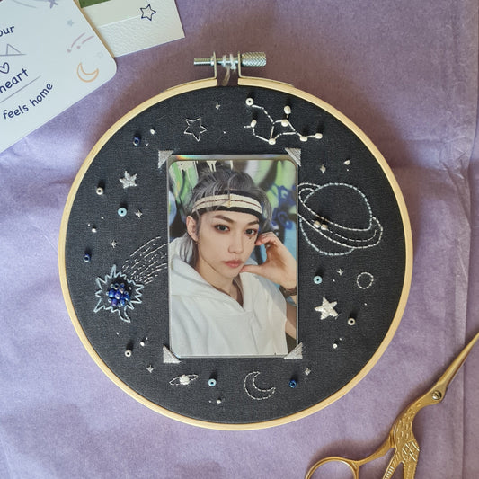 Cadre photo ou pc-holder, cette broderie offre un encadrement rêveur tout en finesse et détails. Lune, étoiles, planète, météore et constellation naviguent autour du cadre pour une ambiance galactique. Les éléments sont brodés en blanc, gris, bleu et argent sur un tissu bleu nuit. Quelques perles viennent agrémenter la broderie. Sur la photo, la pc au milieu représente Felix du groupe Stray Kids. Glissez-y votre photocard ou polaroid favori et donnez lui une place de choix dans votre déco.